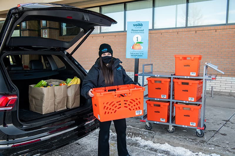 Voilà by Safeway teammate delivers grocery order in designated Safeway curbside pickup parking spot in Calgary, Alberta.
