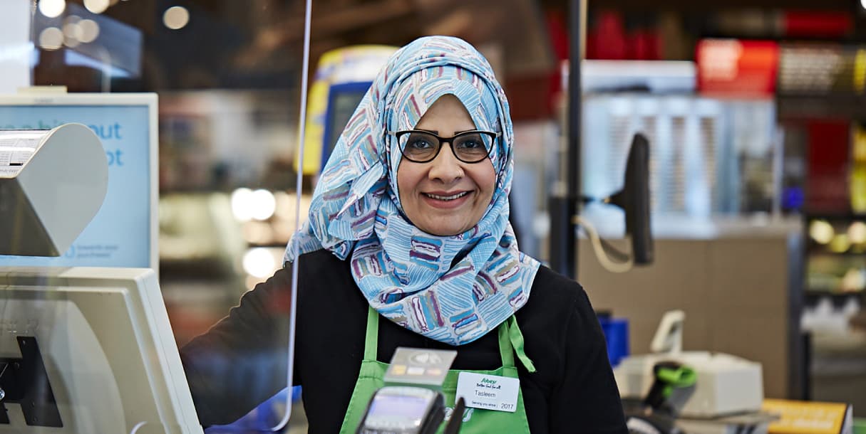 A Muslim woman Sobeys employee smiling at the checkout counter