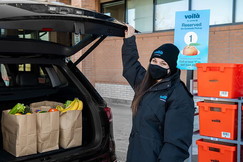 Voilà by Safeway teammate delivers grocery order in designated Safeway curbside pickup parking spot in Calgary, Alberta.