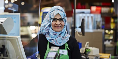 A Muslim woman Sobeys employee smiling at the checkout counter
